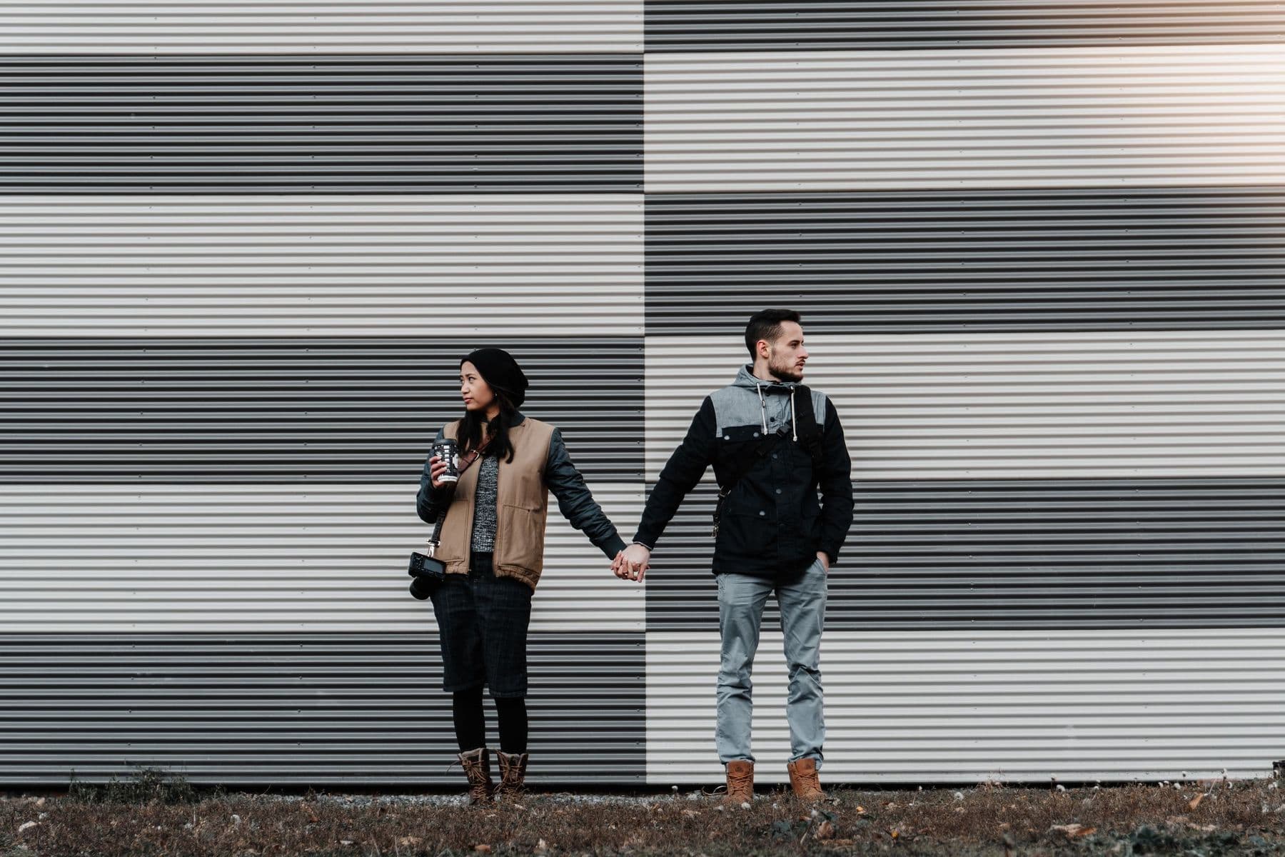 Couple standing close together against a striped wall