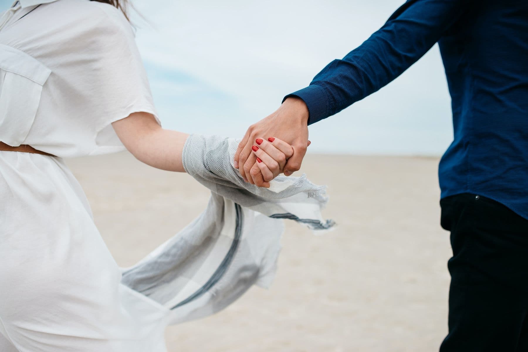Couple holding hands while walking on a beach