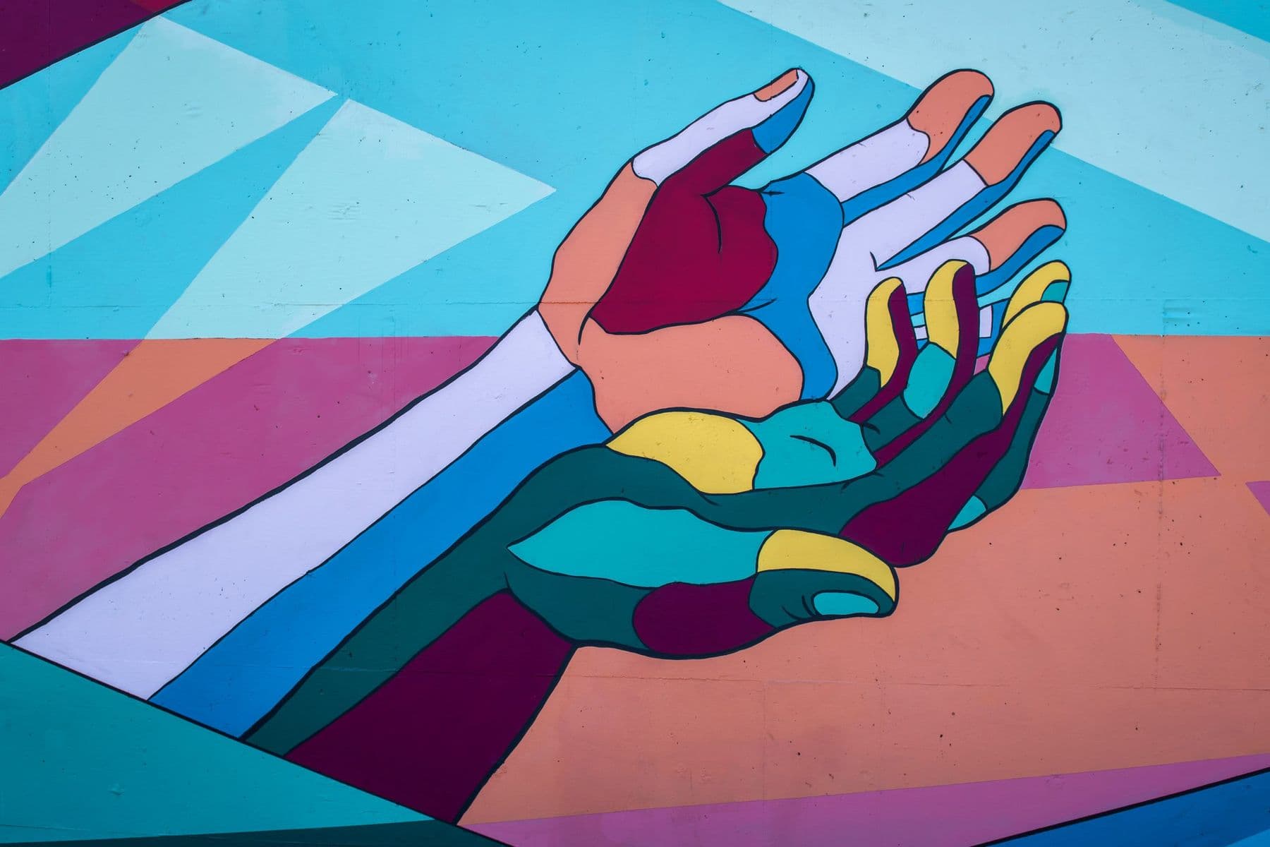 Colorful mural of many hands reaching toward one another