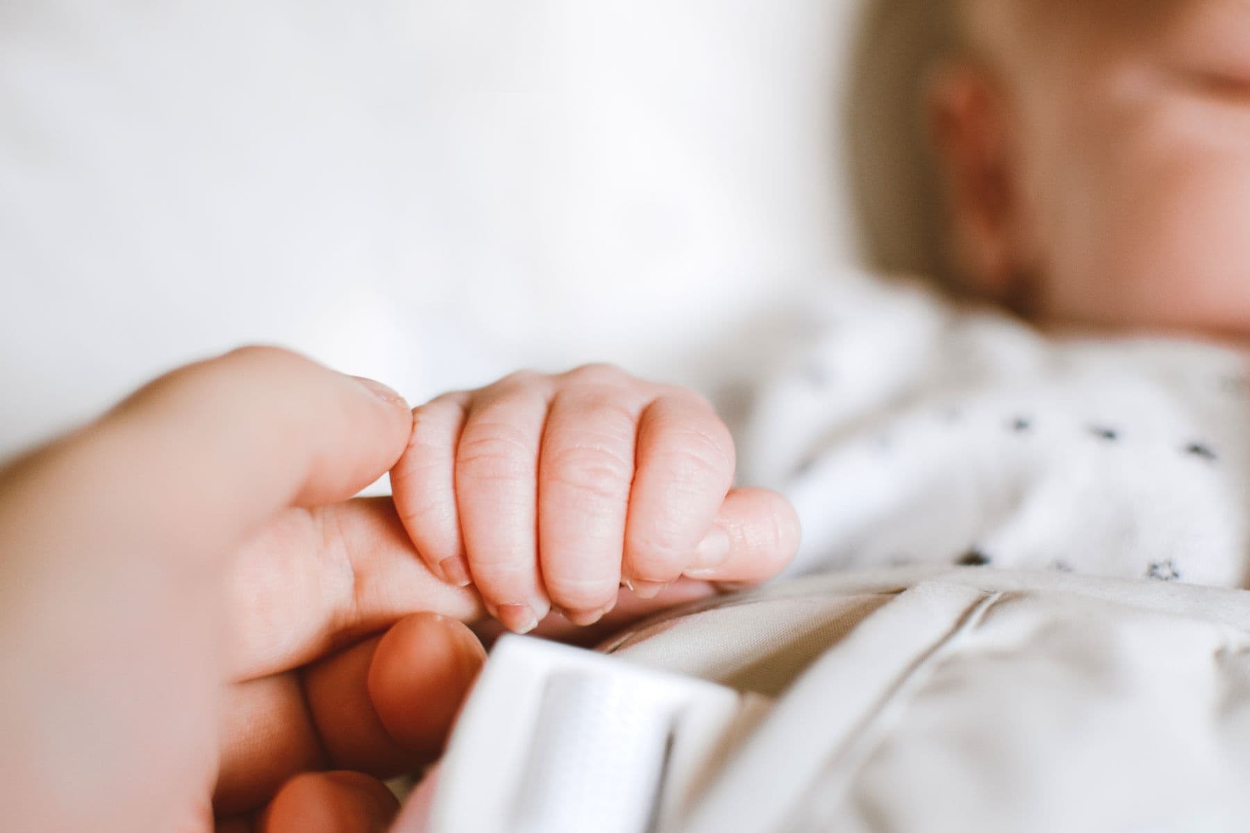 Newborn baby's hand resting in an adult's hand