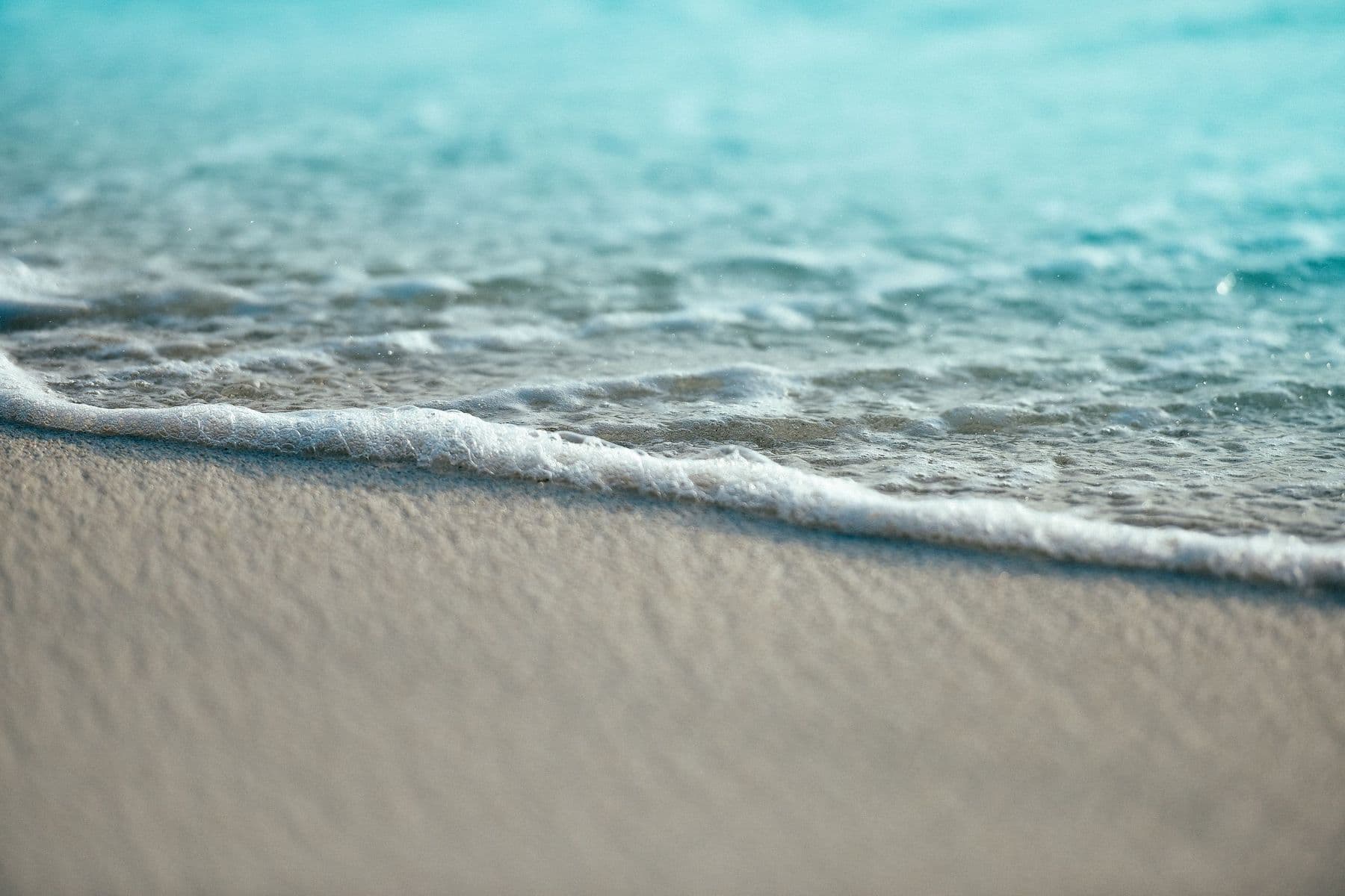 Calm turquoise water washing over a sandy shoreline