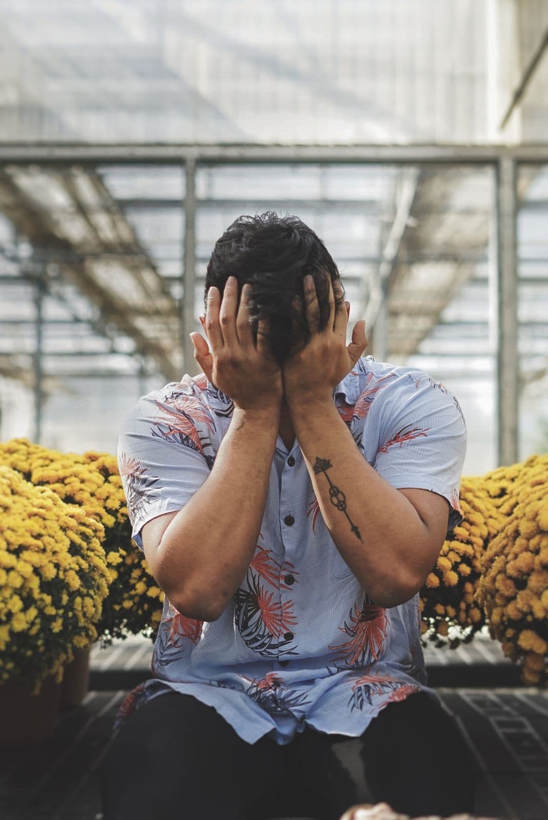 Man sitting with his head in his hands, weighed down by low mood