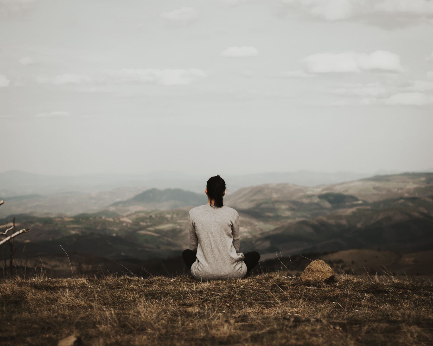 Woman sitting quietly and looking out at a mountain view