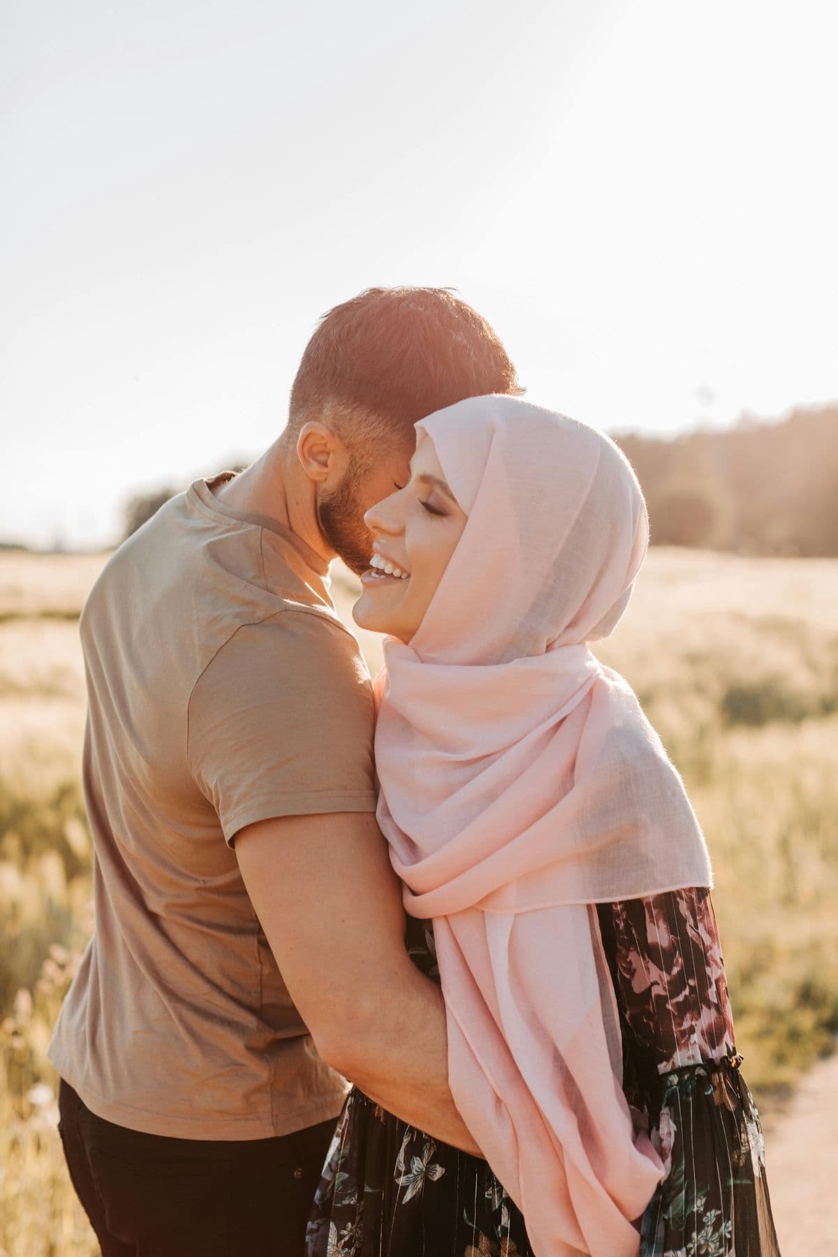 Muslim couple, the woman in a hijab, embracing in an open field