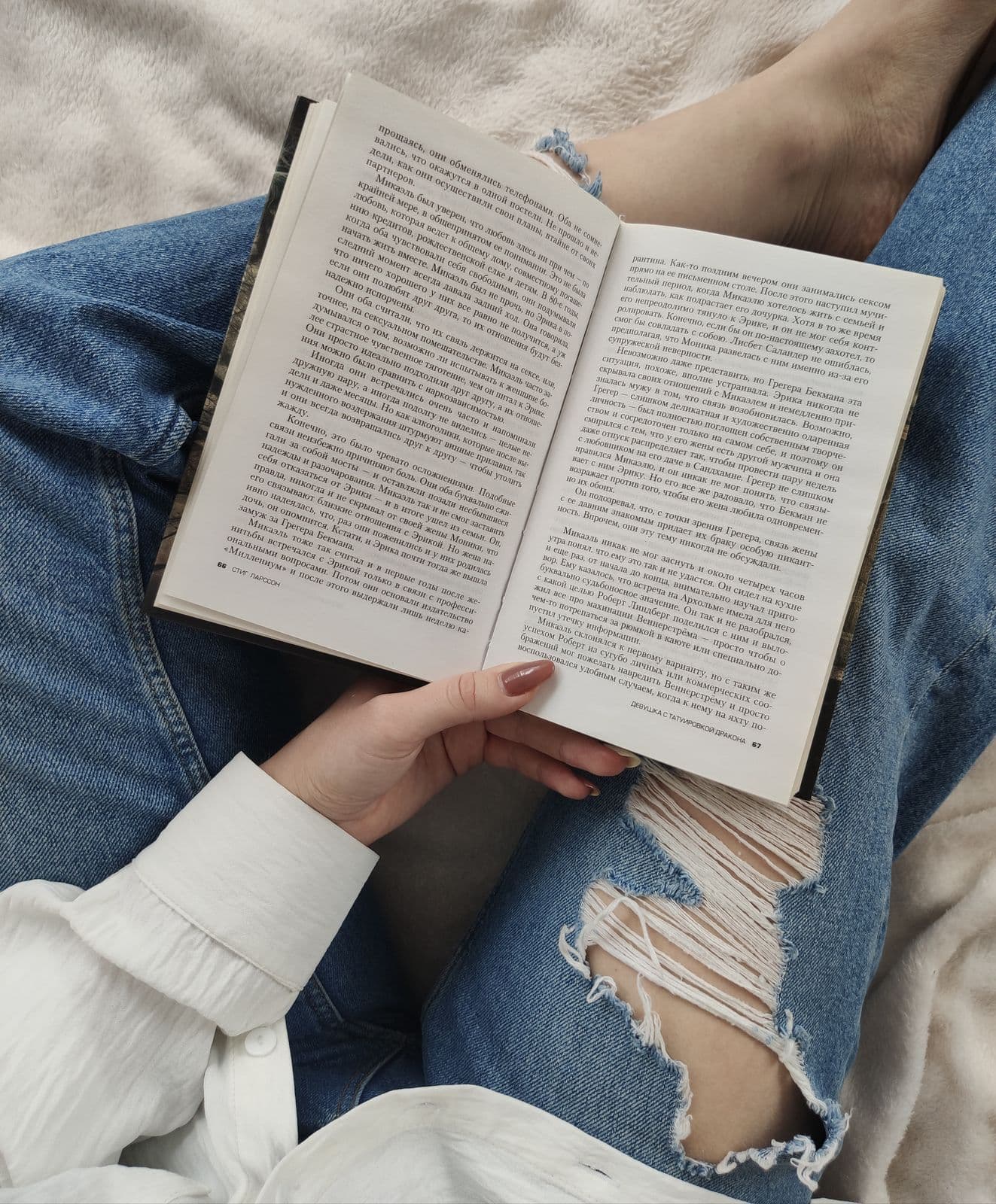 Person reading a paperback book in a cozy blanket