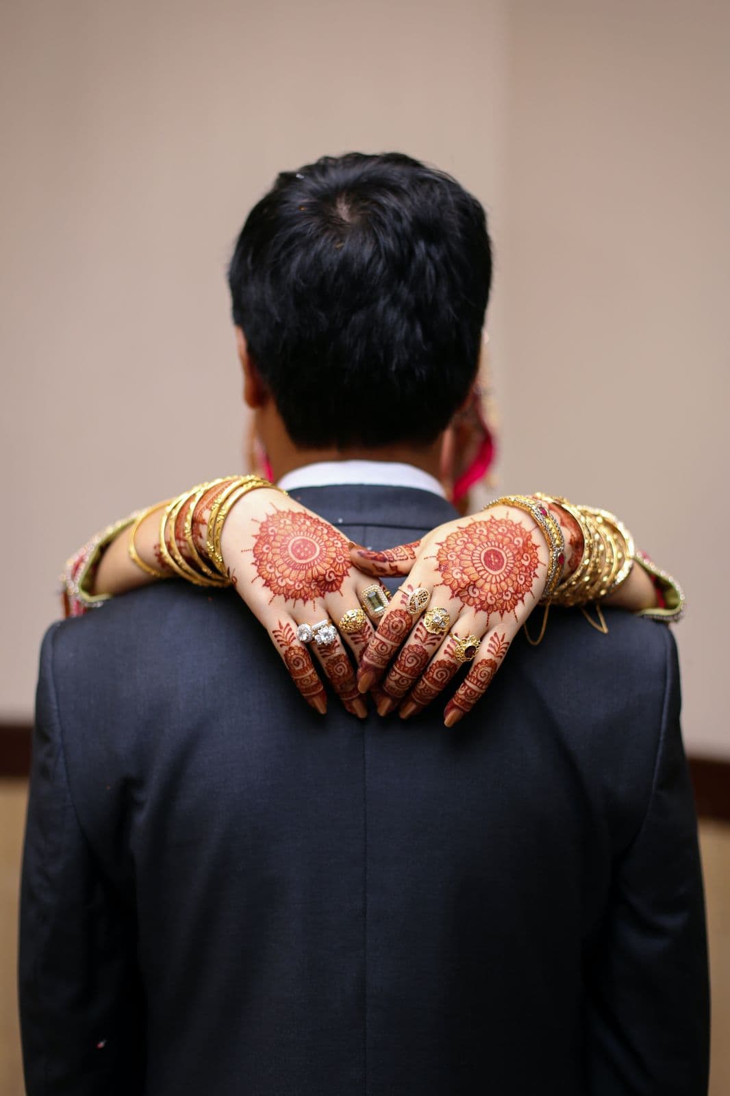 Bride's hennaed hands resting on the groom's shoulders at a South Asian wedding